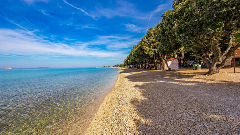 Tree-shaded pebble beach at Straško near Novalja, reachable on foot or by bike from town